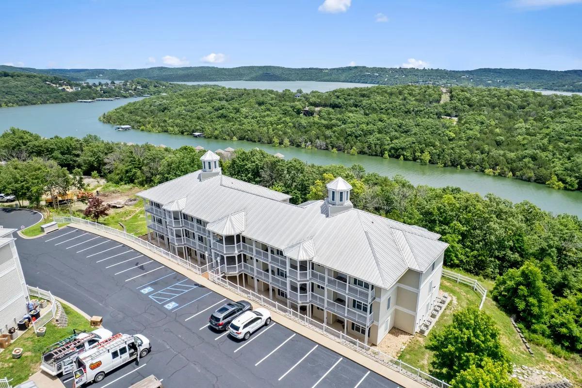 This exterior shot captures the tranquil lakefront, lush greenery, and the building structure nestled beside the water. The image perfectly illustrates the property's prime placement on Table Rock Lake, with inviting access to boating, fishing, and lakeside relaxation.