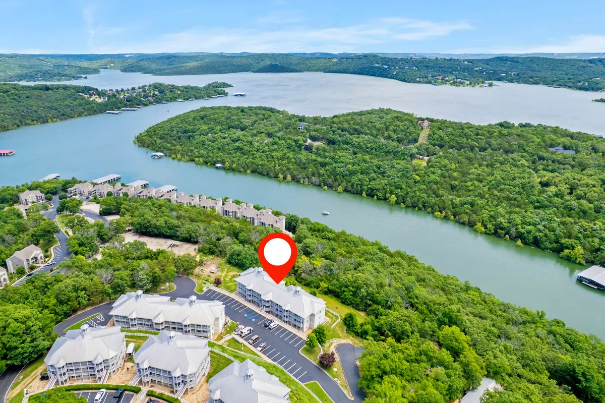 A serene view of Table Rock Lake is framed by surrounding greenery and the resort’s buildings in the distance. The lake beckons with opportunities for boating, fishing, swimming, or simply relaxing by the water.