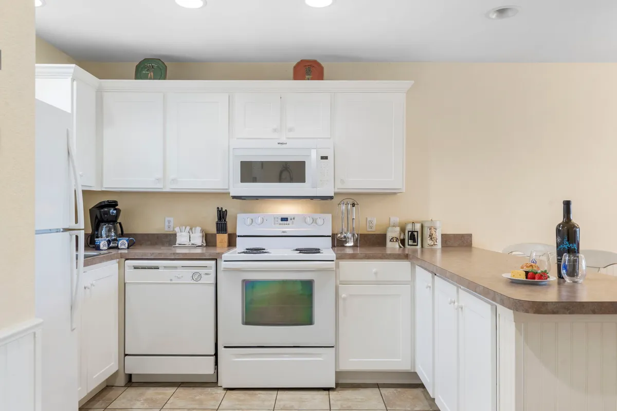A welcoming kitchen with crisp white cabinetry, stainless steel appliances, and a countertop adorned with a colorful fruit arrangement. The space invites both casual and serious cooks to prepare and share meals.