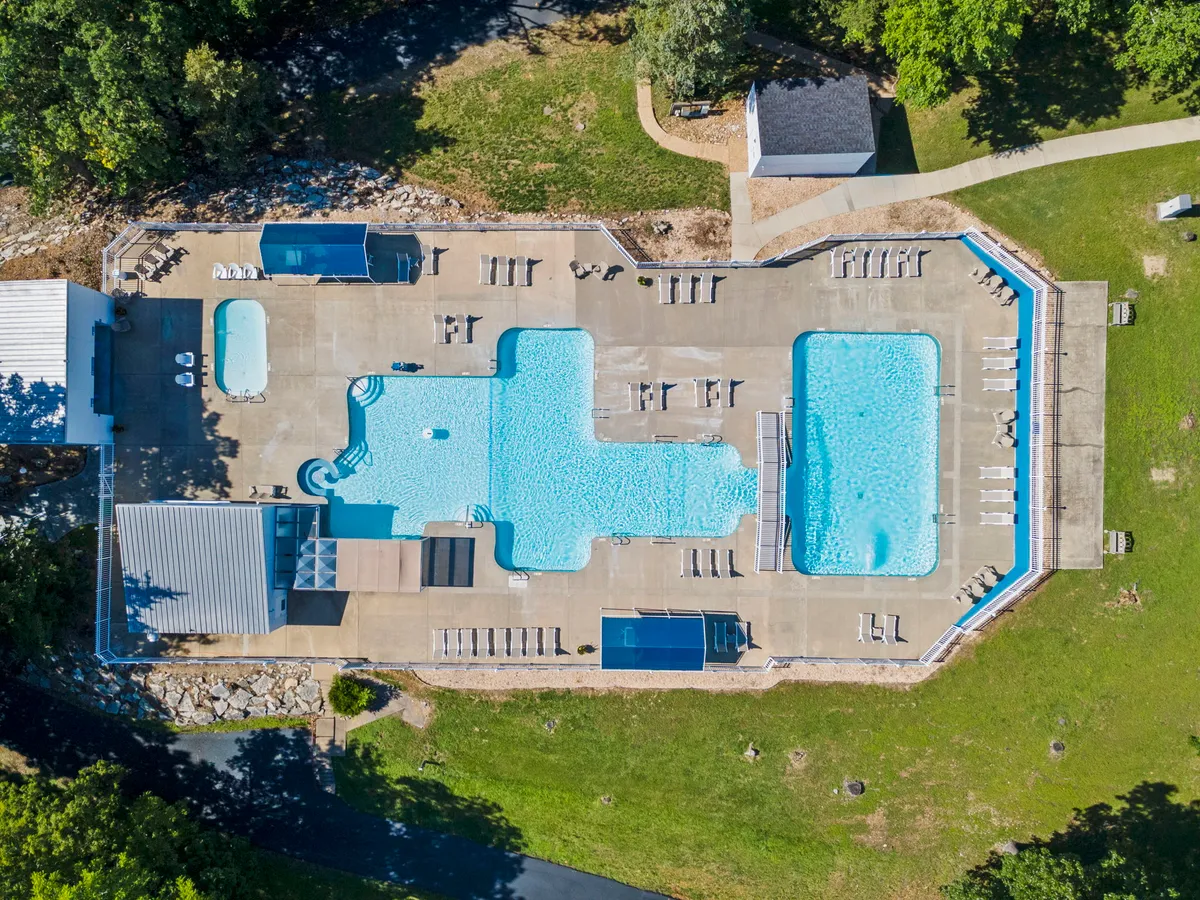 A vibrant exterior view of the resort’s outdoor pool area, surrounded by lounge chairs and green spaces. The pool sparkles under the sun, offering a welcoming spot for swimming, sunbathing, and gathering with family or friends.
